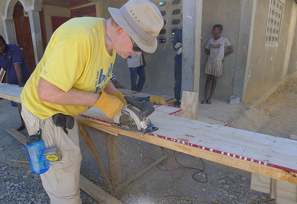 Durham professor James Goedert uses a circular saw to trim a wood joist for the roofing system at Flower of Hope school.